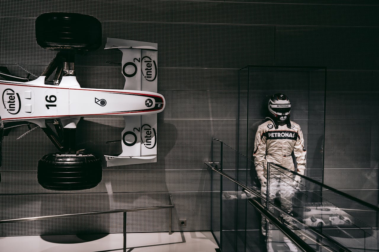 Showcasing a race car and driver suit in a sleek Munich exhibit.